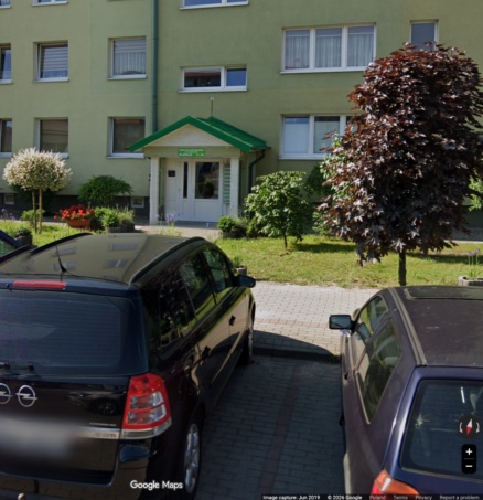 Wejście do klatki B z zielonym daszkiem, widoczne od strony ulicy